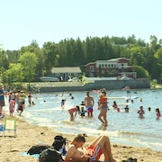 Une plage en été avec des gens dans l'eau et d'autres hors de l'eau.