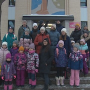 Des parents réunis avec leurs enfants devant une école de Québec.