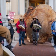 Deux femmes autochtones jouer du tambour devant une section d'arbre gigantesque devant la porte du parlement à Victoria, en Colombie-Britannique. 