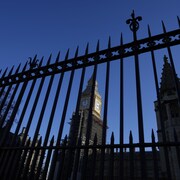 L'édifice du parlement de Westminster, à Londres, vu à travers une clôture grillagée.