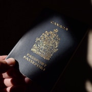 Une main qui tend un passeport canadien