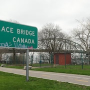 Une pancarte indique la direction du pont Peace Bridge et du Canada. Le Peace Bridge est en arrière plan.