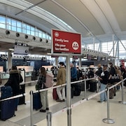 Le guichet d'enregistrement de l'aéroport Pearson de Toronto avec une file d'attente.
