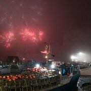 Au port de mer : feux d'artifice, brume et bateaux qui s'élancent pour la pêche