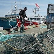 Pêcheur sur le quai avec des cordages et des casiers à homard.