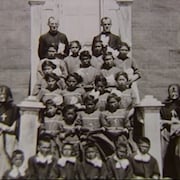 Photo de groupe d'enfants autochtones, avec des religieux et des sœurs autour d'eux.