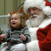 Une fillette pleure en se faisant prendre en photo sur les genoux du père Noël.
