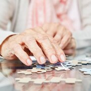 Gros plan sur la main d'une personne âgée qui joue à un casse-tête.