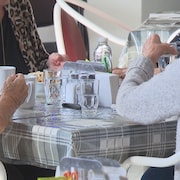 Des dames âgées attablées durant un repas.
