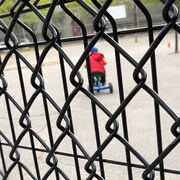 Un enfant se promène en tricycle dans une cour d'école.