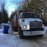 Un camion-benne fait la collecte du recyclage dans un quartier résidentiel.