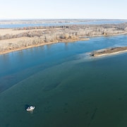 Un bateau flotte près d'une grande structure de pierre submergée.