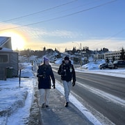 Un homme et une femme marche sur le trottoir dans une rue de Chicoutimi
