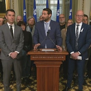 Un groupe de députés en conférence de presse dans une salle au parlement.