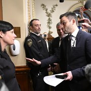 Le chef du Parti québécois Paul St-Pierre Plamondon, au centre, s'adresse au sergent d'armes de l'Assemblée nationale Véronique Michel.