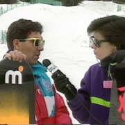 Pierre Vérot et Marie-José Turcotte tiennent chacun une planche à neige. Marie-José Turcotte lui tend un micro. 