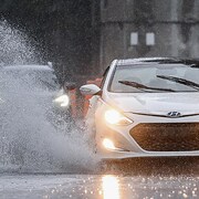 Une voiture projette l'eau accumulée au sol en roulant.