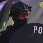 Un policier équipé dun bouclier et portant un masque anti-émeute, à Calgary, le 9 mai 2024.
