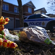 Des fleurs devant une maison où une voiture de police est stationnée.