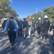 Des manifestants et des agents anti&eacute;meute marchent dans les rues de Longueuil.