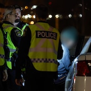 Des policiers arrêtent un adolescent, la nuit.