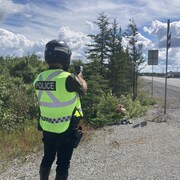 Un policier en bord de route pointe un radar afin de vérifier la vitesse des véhicules.
