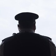 La silhouette d'un policier de dos en contre-jour.