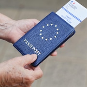 Un homme tient dans ses mains un passeport et une carte électorale.