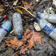 Des bouteilles de plastique vide traînant sur le sol mouillé.