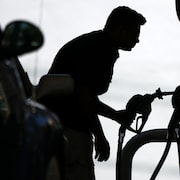 Silhouette d'un homme observant le prix de l'essence à la pompe.