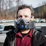 Un homme porte un demi-masque à deux valves qui couvre son nez et sa bouche.
