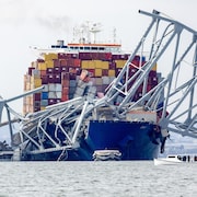 Le porte-conteneurs Dali est immobilisé dans l'eau, sous le pont qui s'est effondré après que le navire fut entré en collision avec lui.