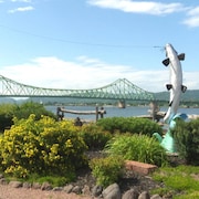 Des monuments qui représentent un pêcheur et un poisson, avec le pont en arrière.