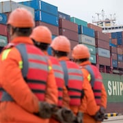 Des travailleurs regardent un cargo s'approcher d'un terminal au port de Qingdao dans le Shandong.