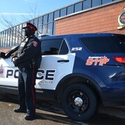 Un policier à côté d'un véhicule de patrouille devant le quartier général de la police de Thunder Bay.