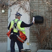 Un facteur dépose une lettre à Rimouski.