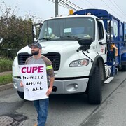 Homme devant un camion avec une affiche.