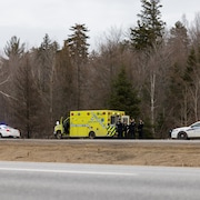 Deux véhicules de police et une ambulance devant un boisé.