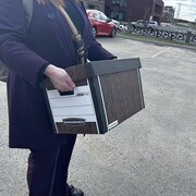 Des avocats à l'extérieur du tribunal transportent des boîtes.