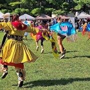 Une femme est des enfants autochtones dansent. 
