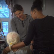 Deux préposées aux bénéficiaires discutent avec une dame âgée au CHSLD.