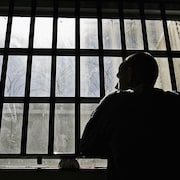 Un homme regarde par la fenêtre d'une prison.