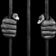 Mains d'un prisonnier sur des barreaux de prison.