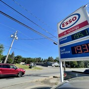 Une voiture passe près d'une pancarte qui indique les prix de l'essence.