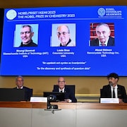 Des gens assis derrière une table, en conférence de presse.