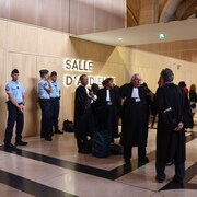 Des gendarmes français et des avocats dans un tribunal.