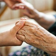 La main d'une personne âgée tenue par une main plus jeune.