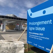 Un panneau annonçant « des travaux préparatoires à la future station de métro [...] dès le printemps 2021 » dans le cadre du projet « Prolongement ligne bleue ».