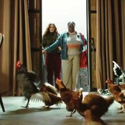Deux femmes ouvrent la porte d'une maison et y découvrent des poulets.