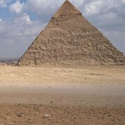 Un chameau se repose avec les pyramides d'Égypte en arrière-plan.